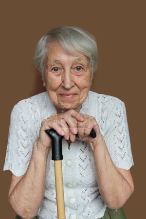Lächelnde Seniorin entspannt sich und hält Spazierstock oder Stock in der Hand. Konzept Hoffnung und Träume