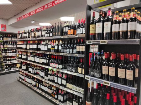 Photo for Strasbourg, Alsace, France -October 21, 2023: Elegant French woman buying red wine alcoholic drinks wines, champagne and whiskey in wine department of a large French supermarket - Royalty Free Image