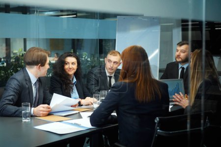 Photo for Team of top managers wearing official clothes having meeting in office behind glass wall. Men and women discussing project, sharing ideas, brainstorming and planning strategy. Concept of business - Royalty Free Image