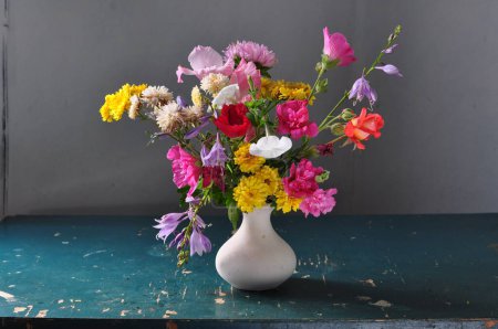 Beautiful bouquet of flowers in a vase on a wooden background