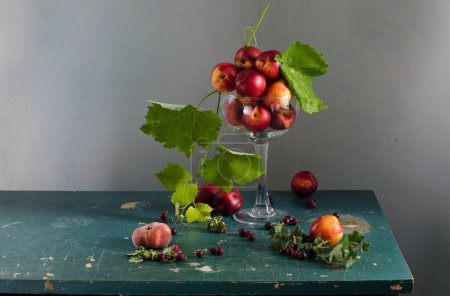 Still life with fresh ripe red and blue apples and a bouquet of red grapes on the old background.