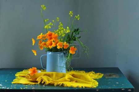 Yellow flowers with blue jug on the table