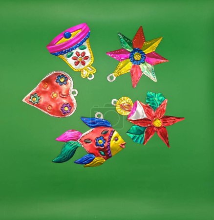 Foto de Cinco estaño decoraciones tradicionales mexicanas de Navidad, fondo verde, campana, vela, corazón, estrella y pescado - Imagen libre de derechos