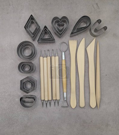 Cutters of different shapes, wooden and metal sculpt tools on cement background