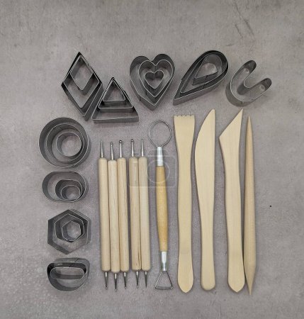 Cutters of different shapes, wooden and metal sculp tools on gray cement background
