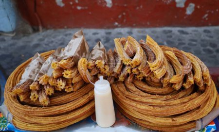 Mexican traditional churros, condensed mil recipient on street stall
