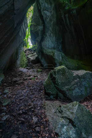 A cave that is open at the top and lets light in through the crack, overgrown with plants. The Kirchle near Dornbirn is a fairytale place, hidden in the forest on a hill. Boulders and moss lie in it