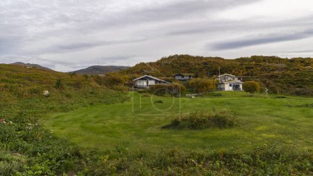 raue Natur im Freien von bunten Haus am Meer, rote und gelbe Häuser an der Küste des Nordatlantiks. Steinige Landschaft mit hölzernem Ferienhaus auf den Inseln Hillesoy, Dorf Sommaroy. Urlaub in Troms, Nordnorwegen.