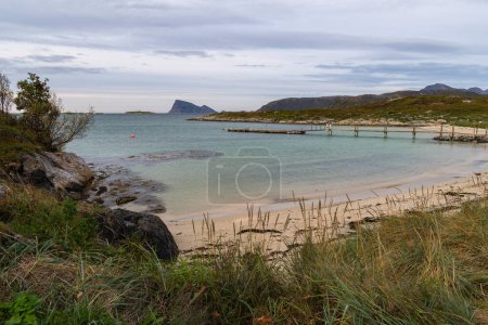Panoramablick mit Jetty am Atlantik bei Sommary, Norwegen. Sandstrand mit Grillplatz und Ruhebereich, am türkisfarbenen Meer, umgeben von Blumen und Büschen. wie in der Karibik! Entspannung im Freien in der nördlichen Wildnis