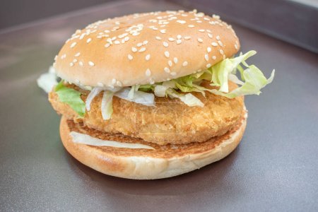 Photo for Chicken burger topped with fresh lettuce, served against a stunning black natural shadow backdrop. A visual delight and selected focus. - Royalty Free Image