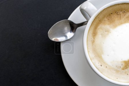 Foto de Cappuccino caliente: Experimente el calor de un cappuccino recién hecho en una taza blanca encantadora, bellamente arreglada en una mesa, vista desde la parte superior. - Imagen libre de derechos