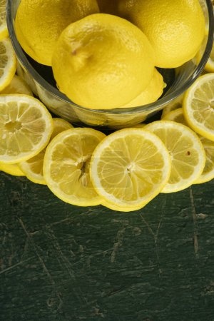 Photo for Whole and sliced lemons arranged in a circular pattern on a green painted rustic peeling old table - Royalty Free Image