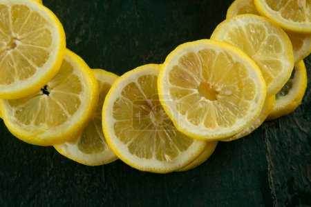 Photo for Whole and sliced lemons arranged in a circular pattern on a green painted rustic peeling old table - Royalty Free Image