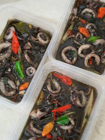 Alimento callejero tradicional indonesio llamado tumis cumi hitam salteado pequeños calamares negros con especias servidas en plato aislado sobre fondo gris