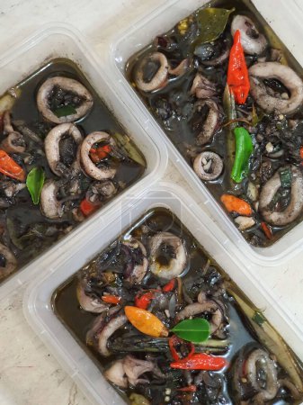 Foto de Alimento callejero tradicional indonesio llamado tumis cumi hitam salteado pequeños calamares negros con especias servidas en plato aislado sobre fondo gris - Imagen libre de derechos