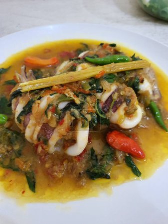 Téléchargez les photos : Tumis Cumi Cabe ou mélanger les calamars frais frits avec du piment vert et du piment thaï rouge, servis dans un bol blanc. Plat traditionnel indonésien. Concentration sélective. - en image libre de droit