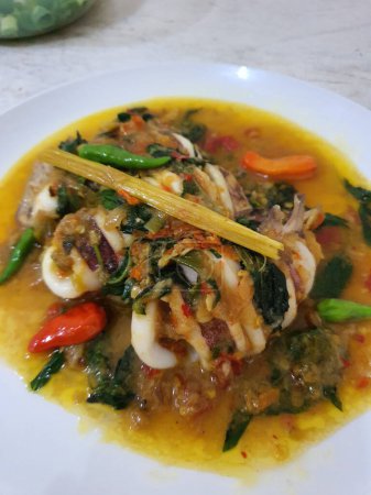 Tumis Cumi Cabe o calamar fresco frito con chile verde y chile tailandés rojo, servido en un tazón blanco. Plato tradicional de Indonesia. Enfoque selectivo.