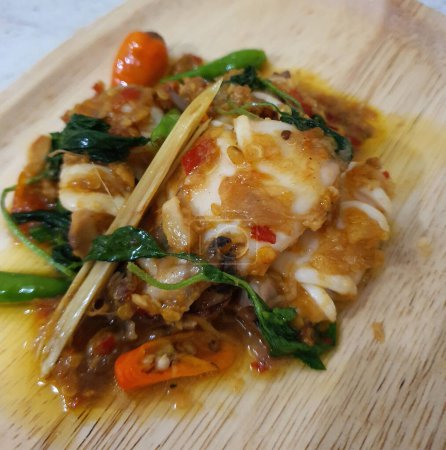 Tumis Cumi Cabe oder rühren frittierten Tintenfisch mit grünem Chili und rotem Thai-Chili, serviert in einer weißen Schüssel. Indonesisches traditionelles Gericht. Selektiver Fokus.