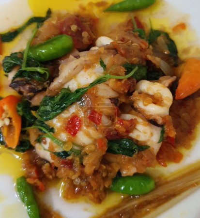 Tumis Cumi Cabe oder rühren frittierten Tintenfisch mit grünem Chili und rotem Thai-Chili, serviert in einer weißen Schüssel. Indonesisches traditionelles Gericht. Selektiver Fokus.