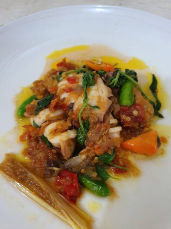 Tumis Cumi Cabe ou mélanger les calamars frais frits avec du piment vert et du piment thaï rouge, servis dans un bol blanc. Plat traditionnel indonésien. Concentration sélective.