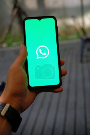 Téléchargez les photos : Rester connecté : Smartphone à main avec logo Whatsapp App visible - en image libre de droit