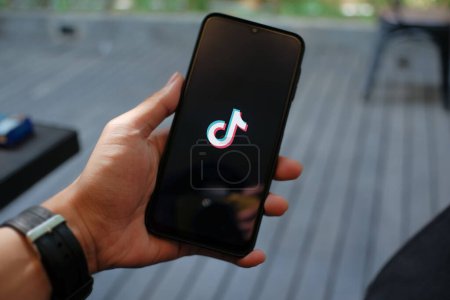 Photo for Staying Connected: Hand Holding Smartphone with Visible Tiktok App Logo - Royalty Free Image
