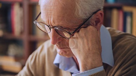 Foto de Mature tired man with gray hair thinking, leaning head on hand, librarian at work - Imagen libre de derechos