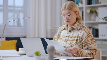 Foto de Una mujer mayor está trabajando como analista financiera desde casa, una contadora experimentada - Imagen libre de derechos