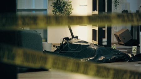 Foto de Un cadáver está tirado en el suelo en una bolsa de plástico, con marcadores de evidencia en una habitación desordenada, lo que significa una escena del crimen - Imagen libre de derechos