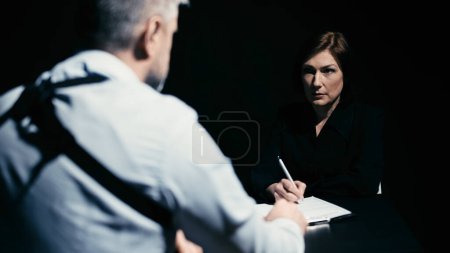 Photo for A woman is signing a confession on paper, confessing a crime to a police detective - Royalty Free Image