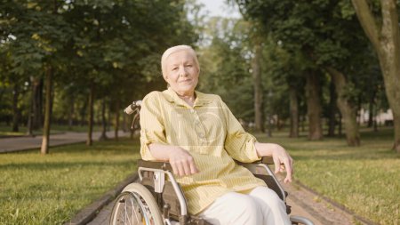 Foto de Feliz mujer mayor con discapacidad mirando a la cámara, caminar en el parque de verano - Imagen libre de derechos