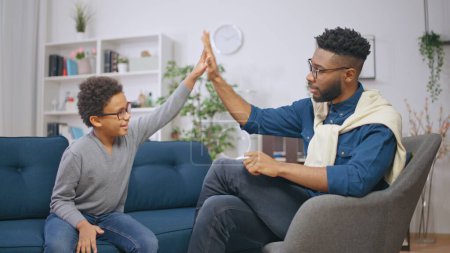 Téléchargez les photos : Psychologue afro-américain et un garçon heureux se donnant cinq après une session réussie - en image libre de droit