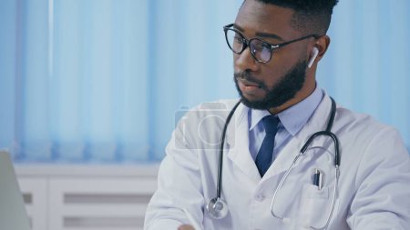 Téléchargez les photos : Thérapeute afro-américain consultant le patient en ligne, écrivant les symptômes, faisant la prescription - en image libre de droit