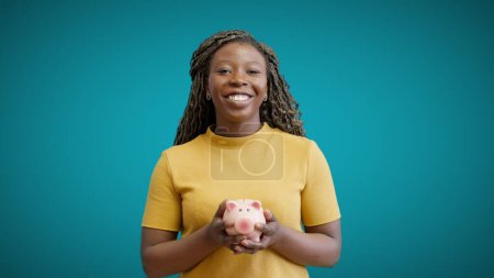 Photo for Happy woman holding piggybank, smiling at camera, bank deposit, income - Royalty Free Image