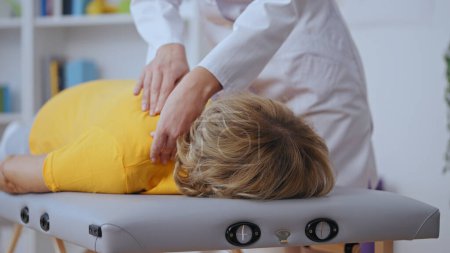 Foto de Primer plano de una paciente acostada en la cama médica mientras el médico examina su hombro, fisiatría - Imagen libre de derechos