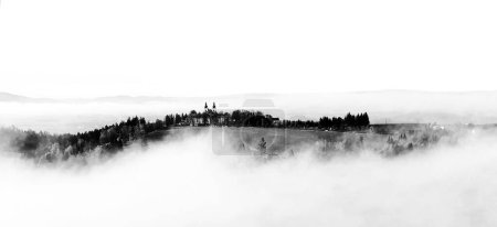 Téléchargez les photos : Illustration noir et blanc. Paysage avec église sur la colline sur le brouillard. Basé sur la montagne de la mère de Dieu dans la ville de Kraliky en République tchèque. - en image libre de droit