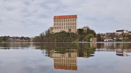Historical Plumlov castle from 17th century and reflection on the surface of the pond in Prostejov district in Czech republic. Cloudy smoke fog air pollution sky.