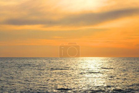 Foto de Hermoso paisaje al atardecer en el mar Mediterráneo y el cielo naranja por encima de ella con impresionante reflejo dorado sol en olas tranquilas. - Imagen libre de derechos
