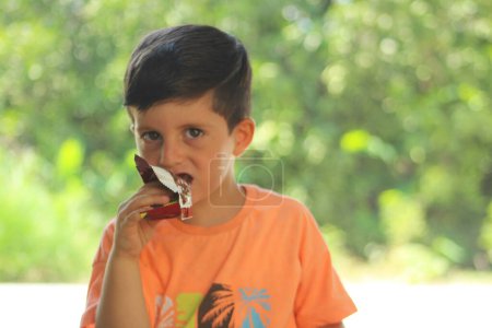 Foto de Niño comiendo oblea cubierta de chocolate. - Imagen libre de derechos