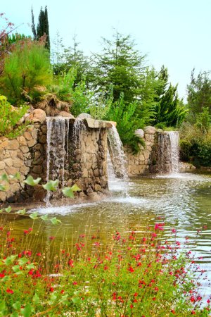 Teich mit Wasserfällen, klarem Wasser und Blumen in einem Park in Arroyomolinos, Madrid (Spanien)).
