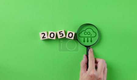 Photo for Carbon Neutrality concept. Magnifying glass with CO2 reduction icon and the word 2050 year on wooden block. Target reduce emission CO2, Carbon footprint, Net Zero, Sustainable energy, Renewable clean, - Royalty Free Image