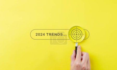 Trends 2024 Jahreskonzept. Hand hält Lupe mit 2024 Trend Suchleiste für Optimierung 2024 Business Marketing Trends und Businessplan im neuen Jahr. Informationen und neue Ideen finden.