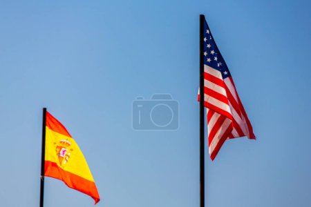 Photo for The national flag of spain and united state of america waving in a blue sky - Royalty Free Image