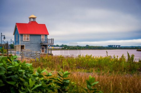 Petitcodiac River and small building with red roof with dramatic sky, Bore Park, Moncton, New Brunswick, Canada. Photo taken in September 2023.