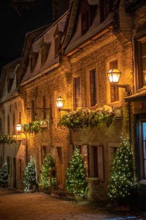 Historical cobblestone street in old lower town, illuminated at night and decorated with Christmas decorations during winter holidays, Petit-Champlain district, Quebec City, Canada December 2022.