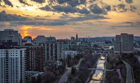 Aerial view of downtown Ottawa at sunset, Parliament Hill, Peace Tower, Rideau Canal, historic Fairmont Laurier hotel, senate, convention centre, Gatineau Hills, Ontario, Canada drone, April 2021