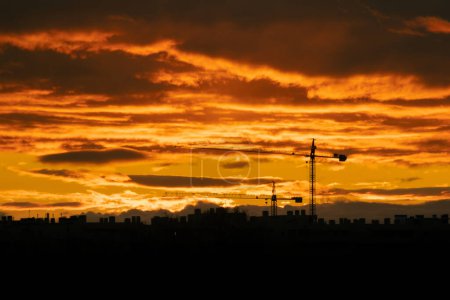 Téléchargez les photos : Coucher de soleil avec grues de construction à l'horizon - en image libre de droit