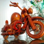 A Miniature Toy Motorbike Made Of Handmade Wood, Placed On A Glass Table