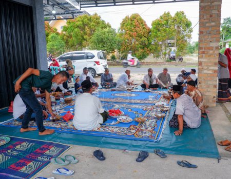 Photo for MUNTOK,INDONESIA - APRIL 17, 2023 : A Group Of People Sitting Cross-legged On The Floor, At A Family Event - Royalty Free Image
