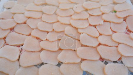 Des morceaux de crevettes craquelins qui sont encore crus et soigneusement disposés dans un plateau